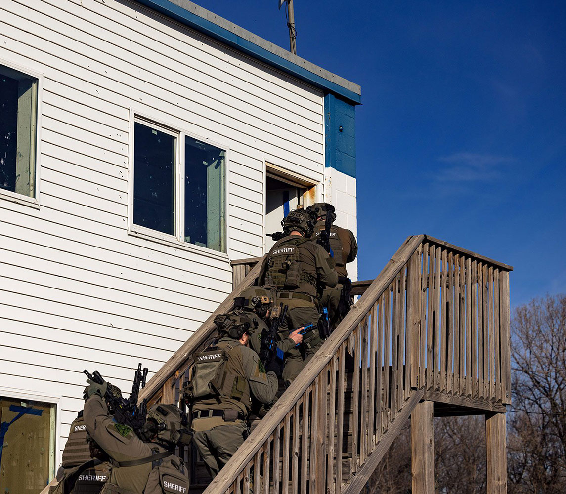 officers lined up on stairs leading into house in hostage rescue training course