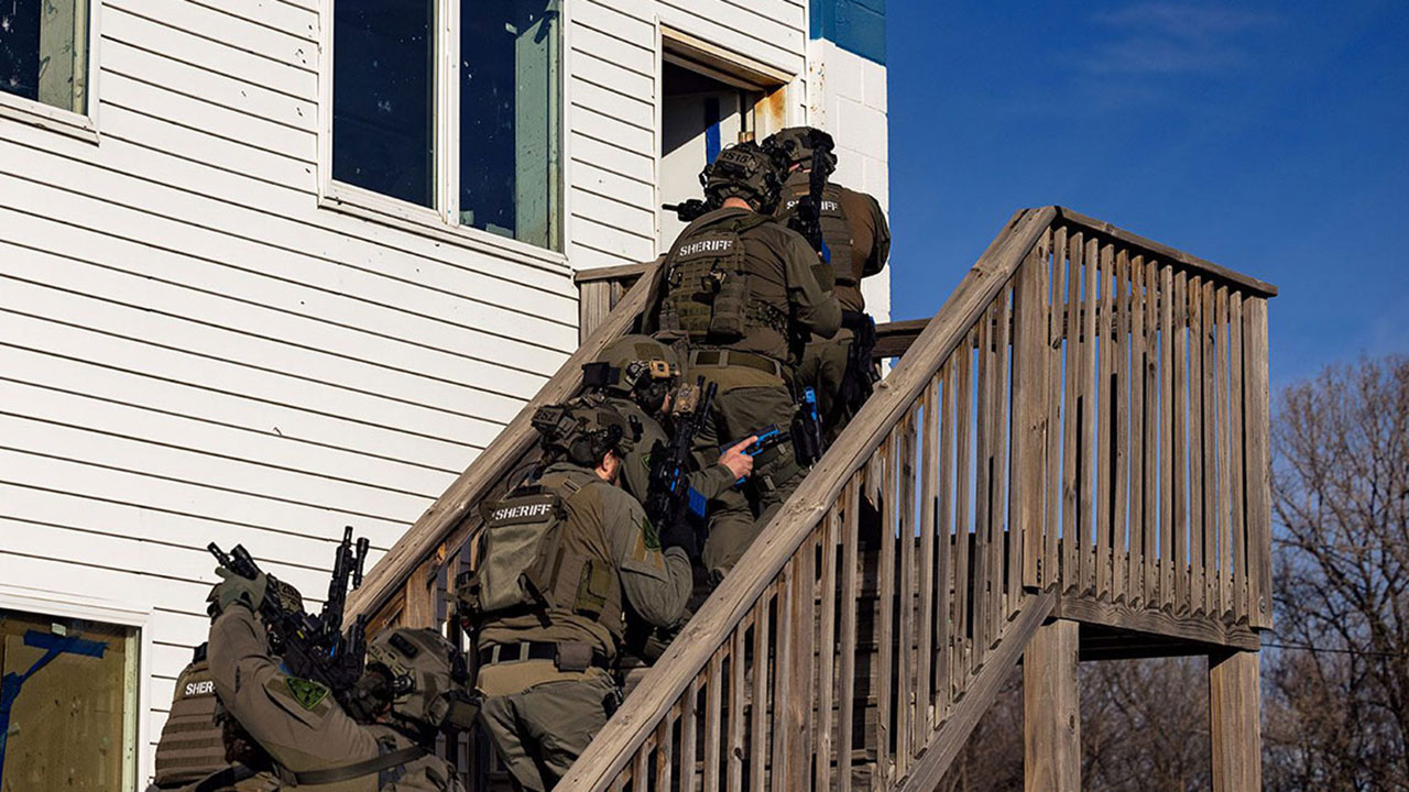 officers lined up on stairs leading into house in hostage rescue training course